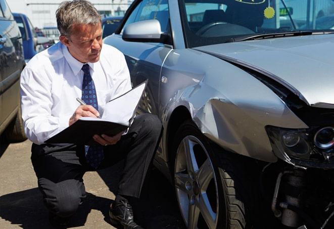 insurance adjuster inspecting a car after a collision